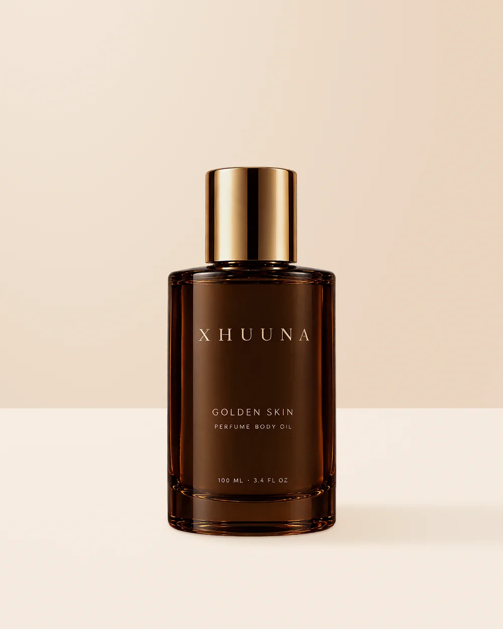 Xhuuna Golden Skin perfume body oil in a dark amber bottle with a gold cap