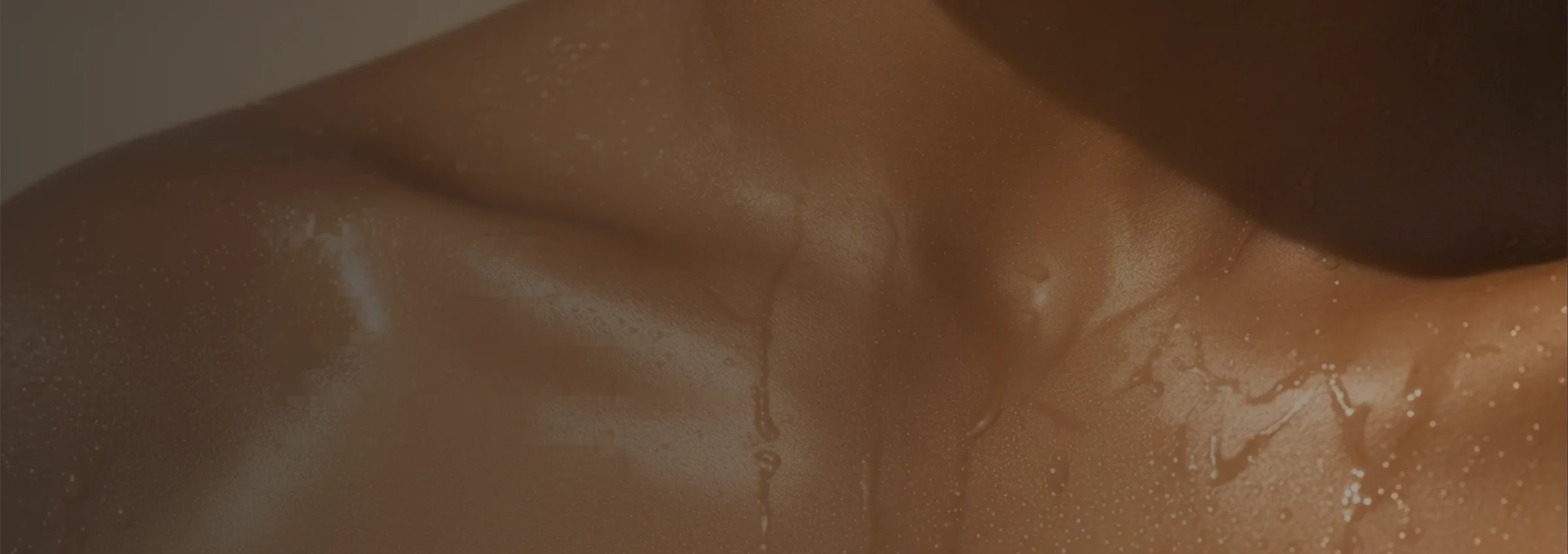 Close-up of golden, oiled skin at the collarbone and shoulder